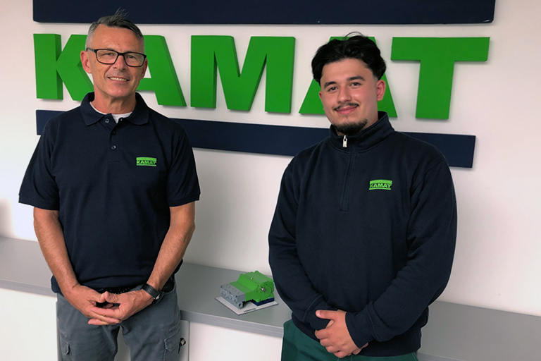 KAMATs new trainee and his instructor in front of the KAMAT Logo